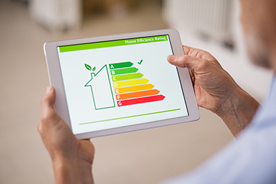 A hand holding digital tablet and looking at house efficiency rating.