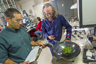 Scientists Brett Singer and Woody Delp cook green beans to test the effectiveness of a range hood.